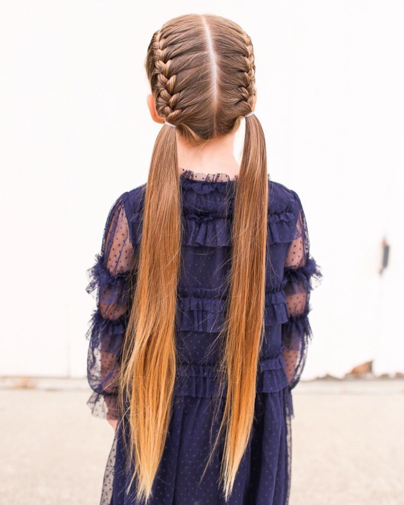 Op de foto draagt een meisje een populair peuterkapsel met franse vlechten die uitmonden in lang ongevlochten haar.