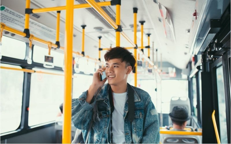Aziatische man op een bus met een choppy bowl cut en een jeans jack met wit tshirt