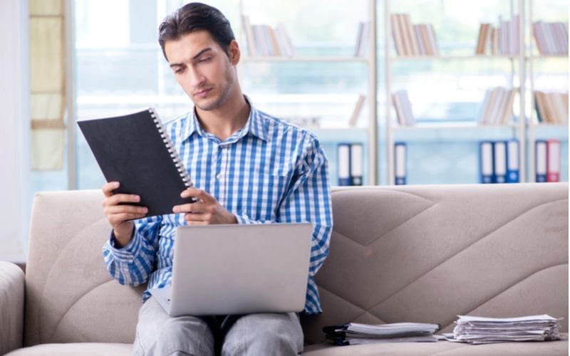 Man in een gingham shirt kijkt intens naar een notebook