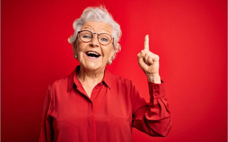 Vrouw met een Curly Casual Crop houdt een vinger omhoog voor een stukje over beste korte kapsels voor oudere vrouw