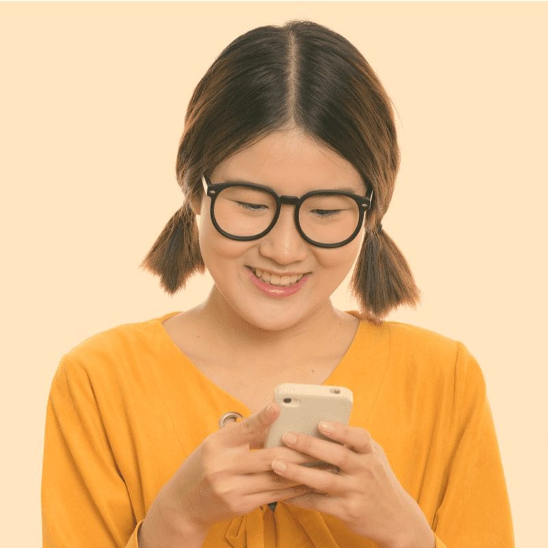 Midi Pigtails met een Aziatische vrouw die glimlachend naar een telefoon kijkt