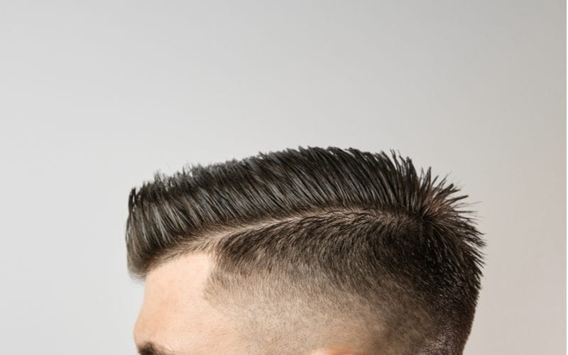 Voor een stuk over kapsels voor kalende mannen, styling van het haar na de kapper op de grijze achtergrond. Concept voor behandeling van haaruitval.