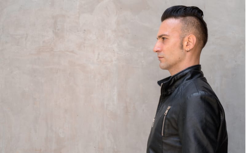 Profielaanzicht van knappe jonge Italiaanse man met undercut die een zwart leren jack draagt