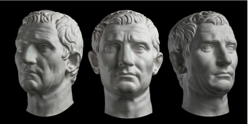 Drie gipskopie van oud standbeeldhoofd van Guy Julius Caesar geïsoleerd op zwarte achtergrond. Het gezicht van de de mens van het gipsbeeld.