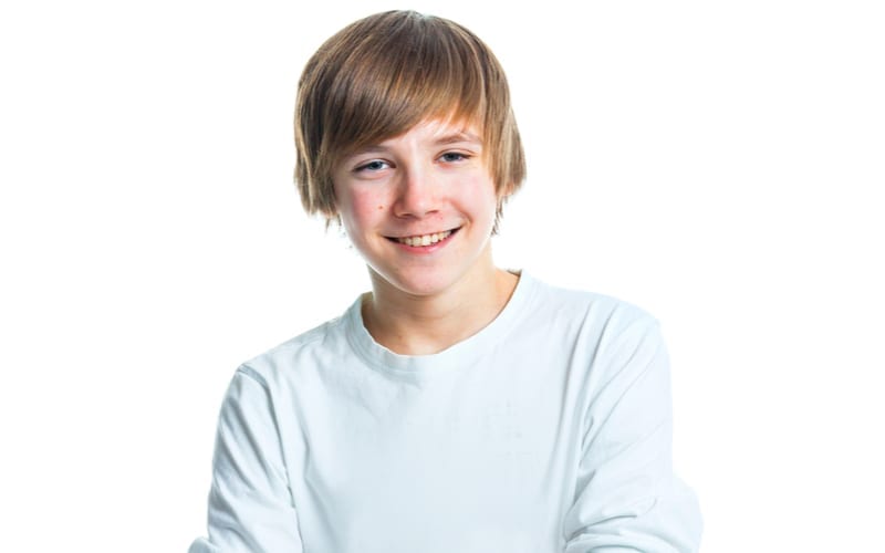 Als afbeelding voor een stuk over tienerkapsels voor jongens, Close-up portret van jonge lachende schattige tiener in het wit, geïsoleerd op wit