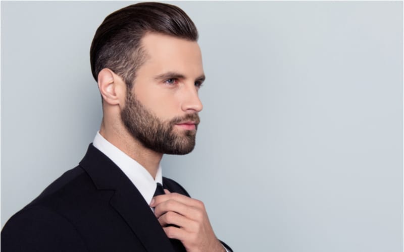 Half gezicht portret van stijlvolle trendy knappe man met modern kort kanten lang topkapsel geïsoleerd op grijze achtergrond copy-space