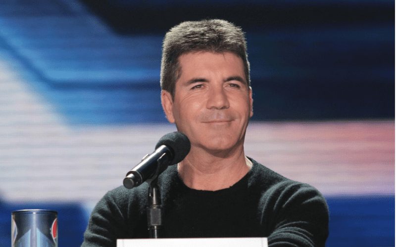 Simon Cowell van The X Factor staat voor een microfoon voor een stuk over slechte kapsels