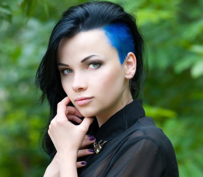 Urban punk girl met een geschoren kapsel voor vrouwen dat half geschoren is en blauw aan de zijkant met een lange top