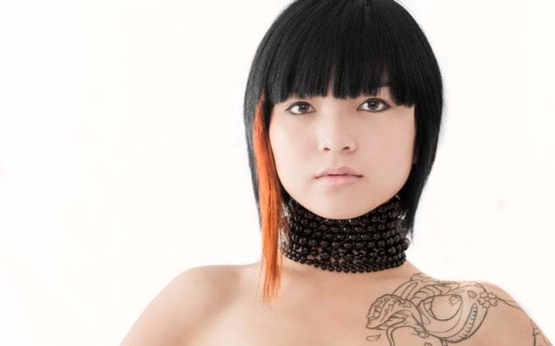 Zeer trendy Aziatische vrouw met een kort kapsel draagt een halsketting en heeft een drakentatoeage