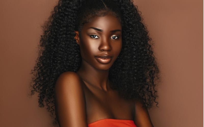 Afrikaans mooi vrouwenportret. Brunette krullend kapsel jong model met donkere huid en perfecte glimlach