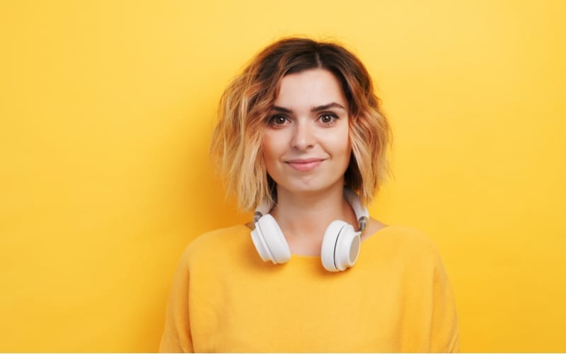 Portret gelukkige smily jonge sexy meisje luisteren naar muziek in witte koptelefoon op een geïsoleerde gele achtergrond. Plezier. De emoties van mensen. Monotoon. Kopieer ruimte