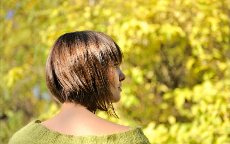 Mooie jonge vrouw die korte shag kapsel herfst buiten draagt, focus op een haar.