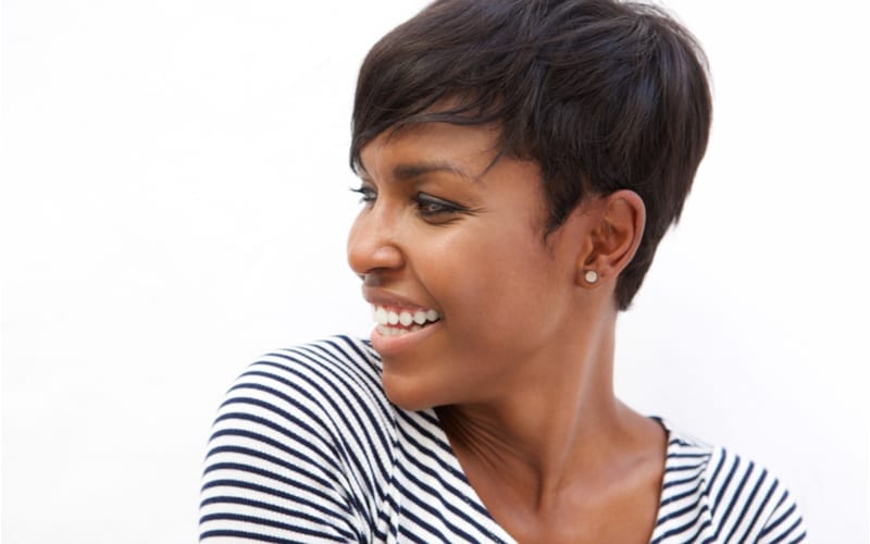 Close up portret van een jonge afrikaanse amerikaanse vrouw met een kort kapsel die glimlacht en wegkijkt
