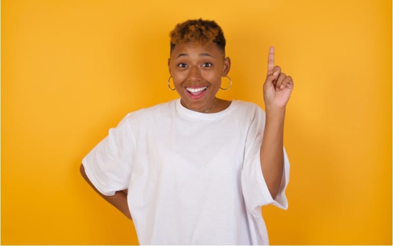 Jonge afrikaanse amerikaanse vrouw met een kort kapsel dat gelegenheidskleren draagt die vinger omhoog het hebben van idee houden en stellen
