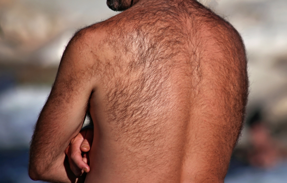 Man met veel haar op zijn rug kruist zijn armen