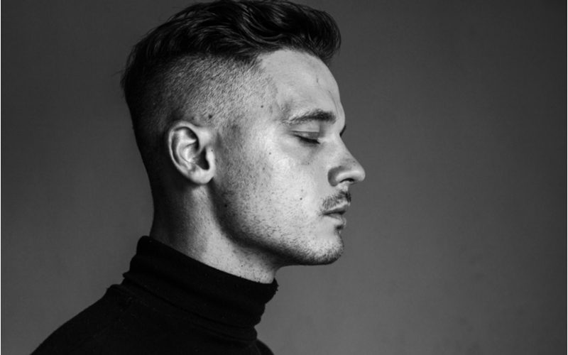 Man met een undercut fade sluit zijn ogen in een zwart-wit foto