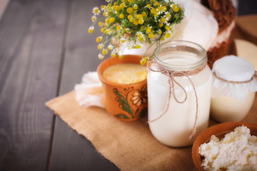 Voor een FAQ sectie over geitenmelk voordelen voor haar, een potje melk naast bloemen op een tafel