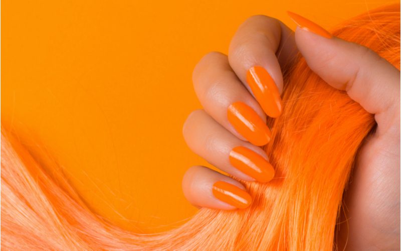 Vrouwen die blauwe toner willen gebruiken voor oranje haar met oranje nagels