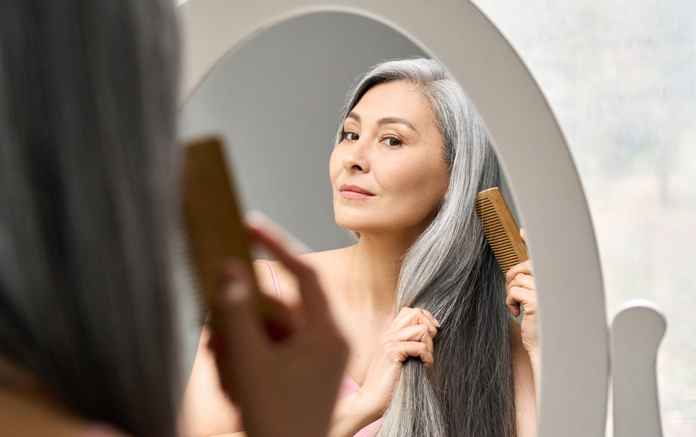 Vrouw kijkt in de spiegel naar haar grijze haar