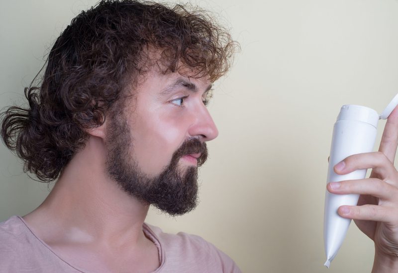 Jonge man met grof vettig haar die de beste shampoo voor vet haar mannen nodig heeft