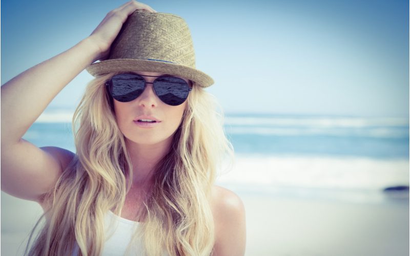 Vrouw die net de beste stijltang voor strandgolven heeft gebruikt draagt een hoed