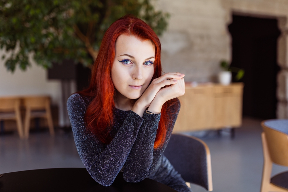 Vrouw met rood haar kijkt naar de camera voor een stukje over de beste haarkleur voor neutrale huidtinten