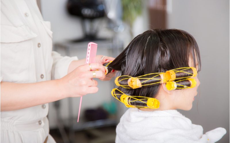 Vrouw die een van de populaire soorten permanenten in haar haar krijgt met rollers