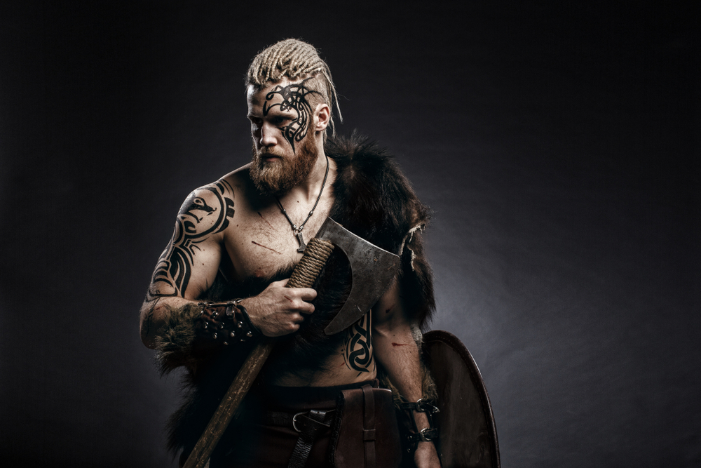 Voor een stuk met de titel: Hadden Vikings dreads? Een man met zo'n kapsel staat in een donkere kamer met een bijl in zijn hand.