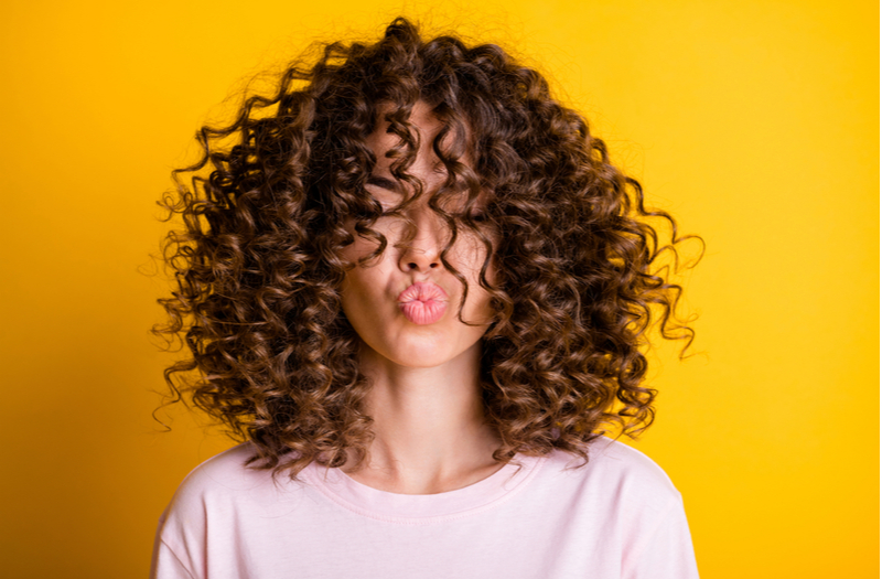 Vrouw met het 3B haartype met krullen die haar ogen bedekken