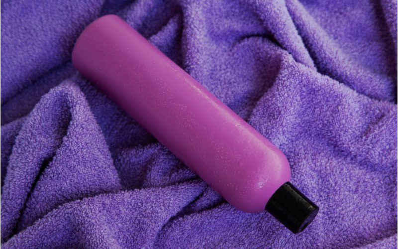 Beeld dat toont hoe paarse shampoo te gebruiken op droog haar met een fles zittend op een paarse handdoek