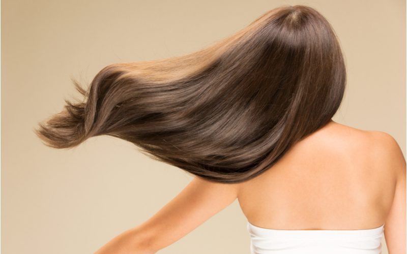 Dingen om te overwegen bij het leren hoe je glanzend haar krijgt bij een vrouw met wapperend haar in de wind en in een strapless shirtje