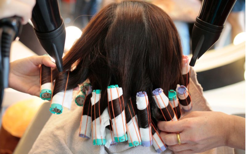 Vrouw krijgt een permanent met haarrollers in een salon om te helpen beantwoorden hoe lang moet het haar zijn om een permanent te krijgen