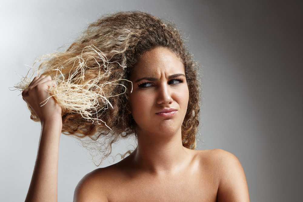 Vrouw vraagt zich af is ontwikkelaar bleekwater, gezien door een vrouw die stro tegen haar hoofd houdt