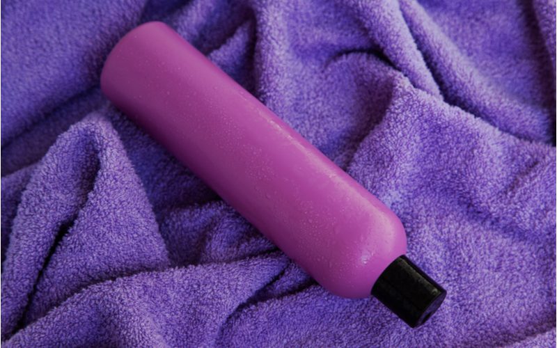 Fles paarse shampoo op een paarse handdoek