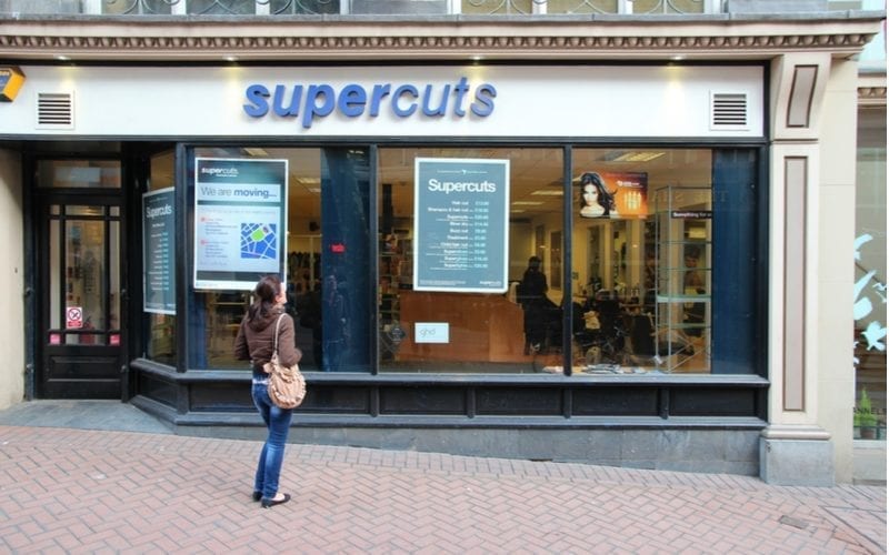 Als beeld voor een stuk over Supercuts uren, staat een persoon buiten een winkellocatie