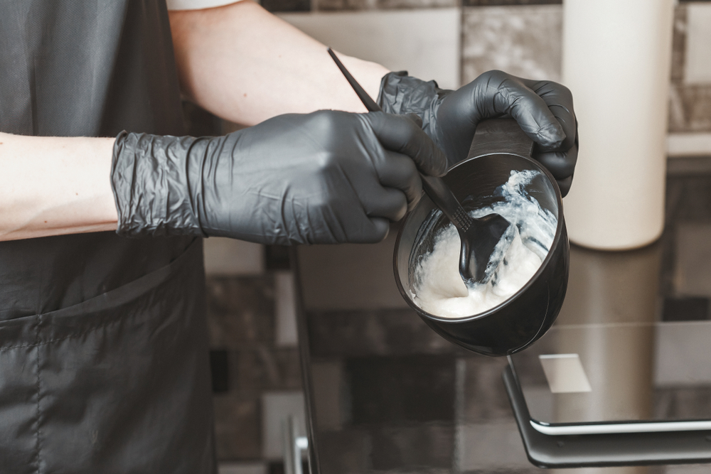 Handschoenen kapper mengen een kom van kleur voor een stuk over does hair bleach verlopen