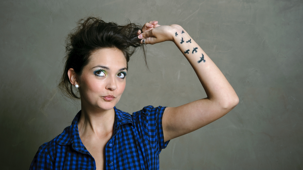 Vrouw speelt met haar haar omdat ze angstig is met vogel tatoeages op haar onderarm