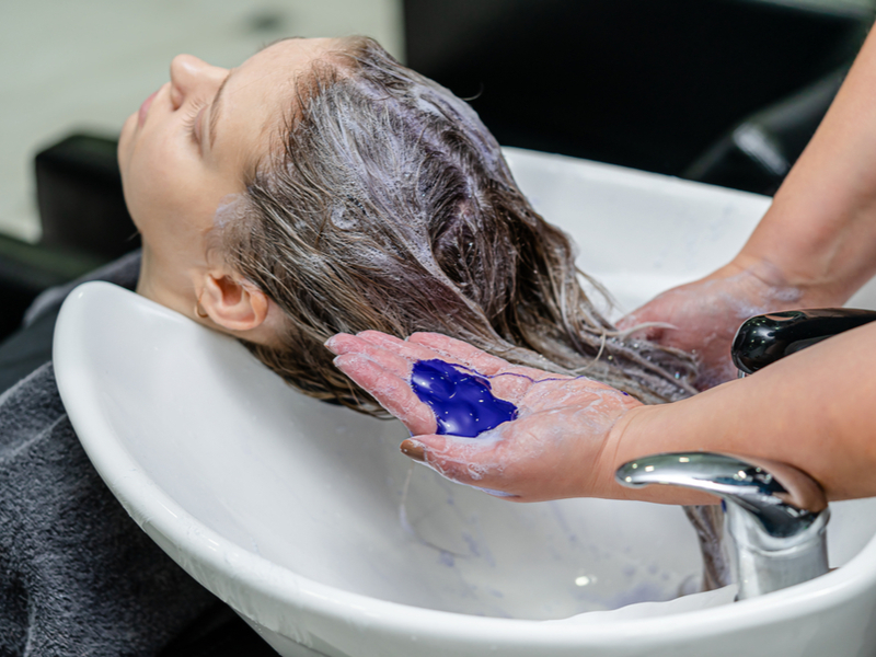 Stuk over wat is haarvlek met een vrouw die paarse shampoo gebruikt