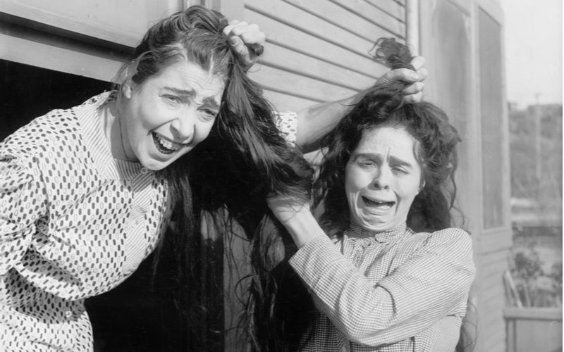 Zwart-wit foto van twee vrouwen die aan elkaars haar trekken voor een stukje over wat is haarkloven?