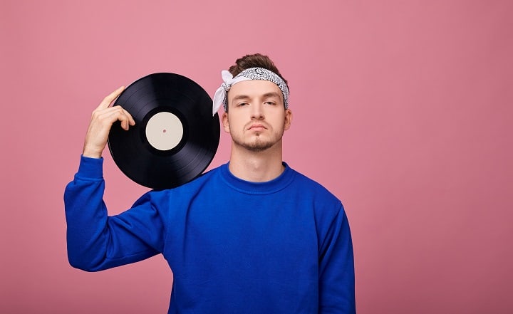 Man die een bandana draagt met een zwarte vinylplaat in zijn hand