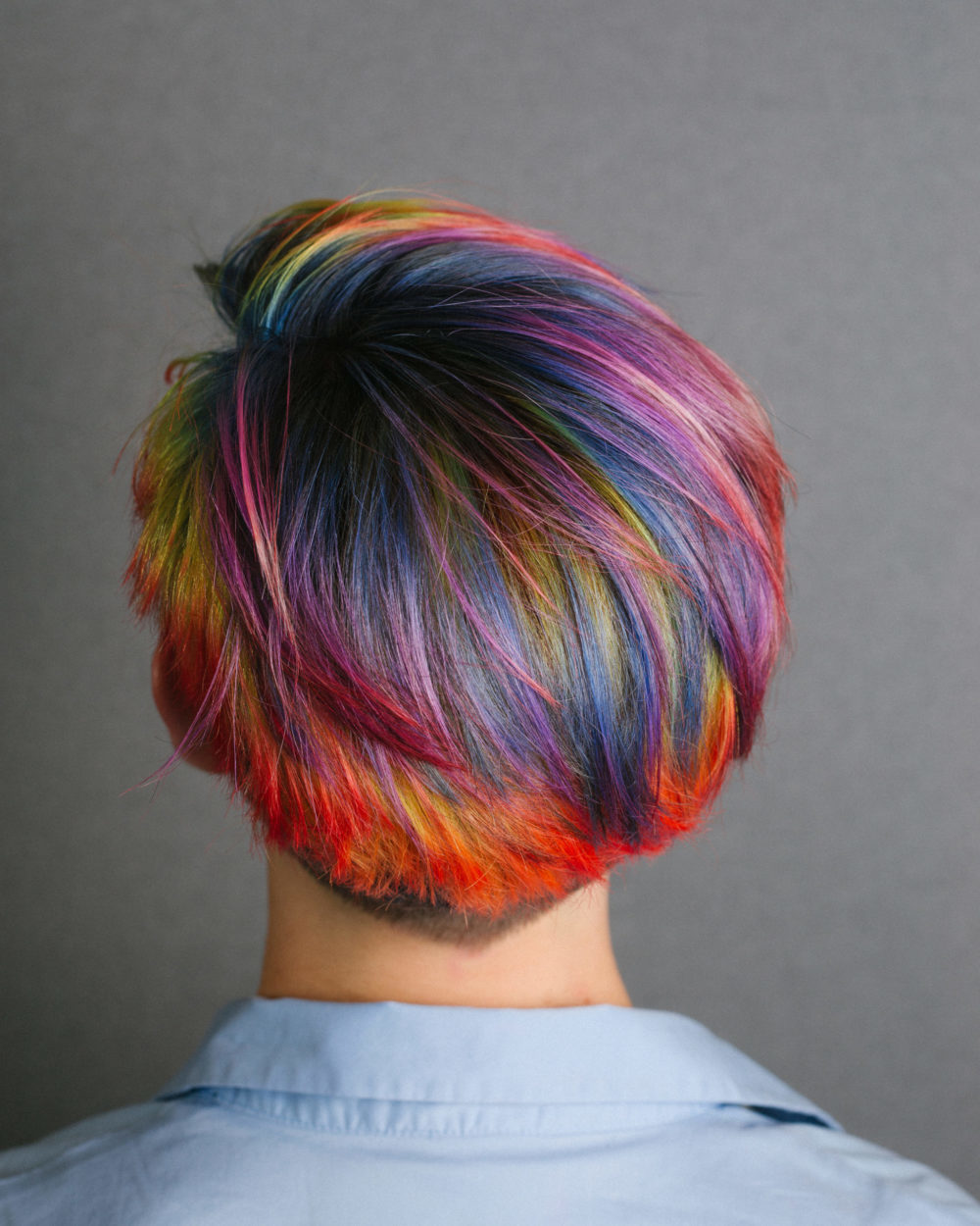 Helder regenboog haar op een vrouw in een blauw shirt