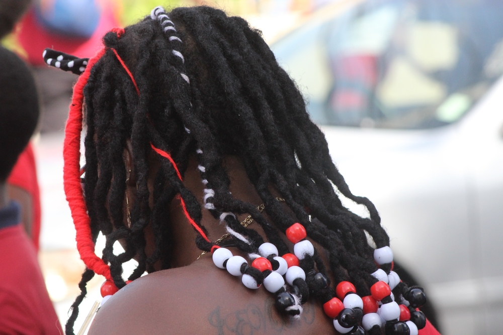 Port of Spain, Trinidad - 31 augustus 2022: Rasta dame met kralen in haar haar die de kleuren van de nationale vlag voorstellen op Trinidad en Tobago's 60e Onafhankelijkheidsverjaardag parade voor een stuk over vlechten met kralen.