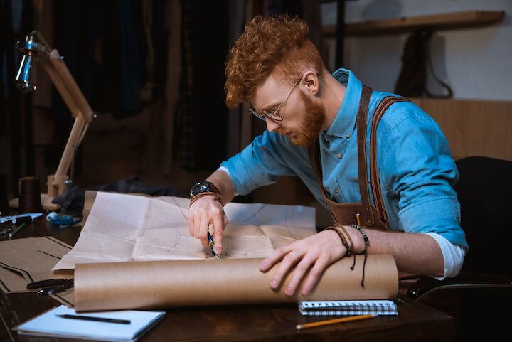 Man met bril en rood krullend haar werkt aan een project