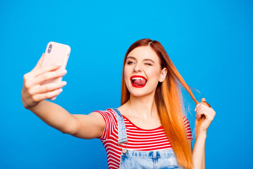 Vrouw neemt een selfie in jeansoverall voor een stukje over rood haar bijschriften voor instagram