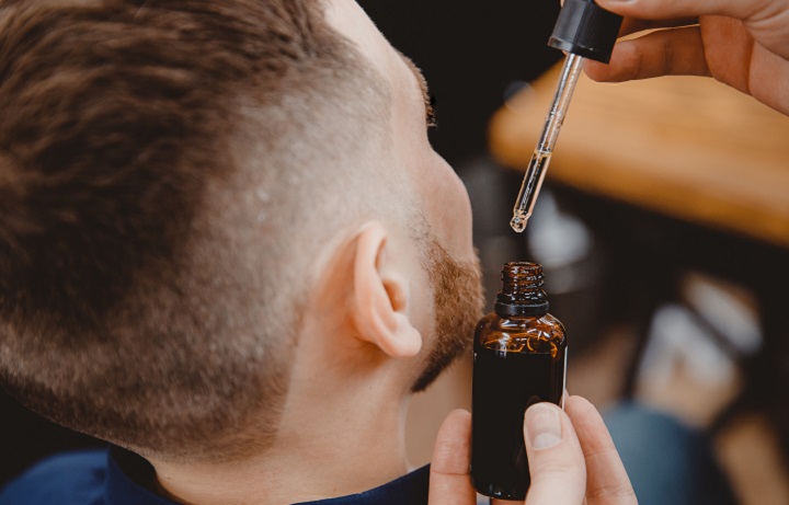 Barber die olie op de baard van een man smeert