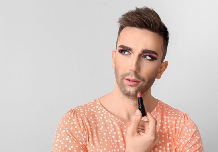 Trans man met baard die lippenstift aanbrengt