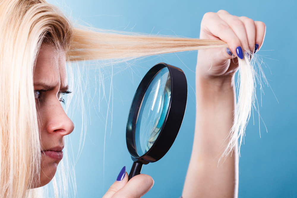 Vrouw kijkt naar haar beschadigde haar en vraagt zich af wat de beste producten voor beschadigd en gebleekt haar zijn.