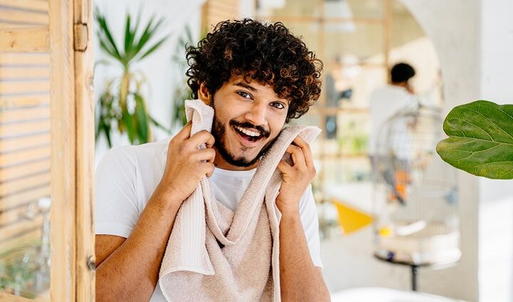 Man met krullend haar die zijn baard droogt