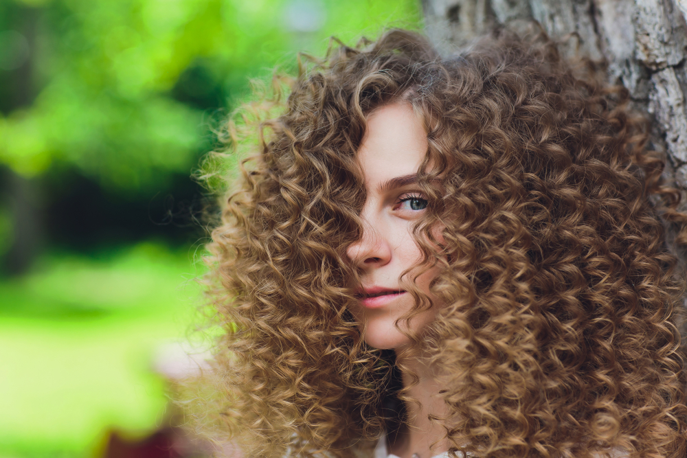 Voor een stuk over de beste haarkleuren voor krullend haar, een vrouw met Lichtbruin en Honingblond Balayage