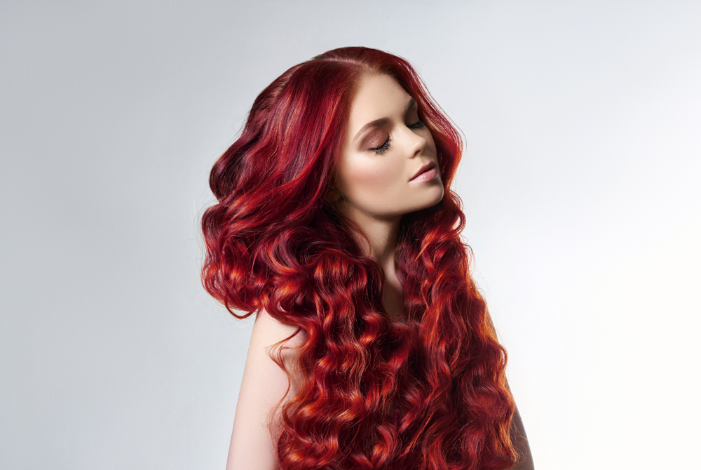 Vrouw met vuurrode balayage in een studio voor een stuk over de beste haarkleuren voor vrouwen met rood haar